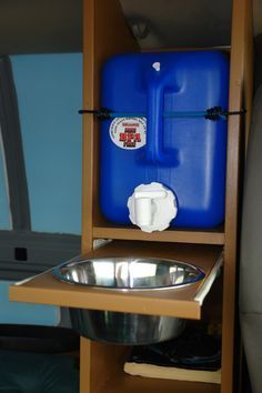 a metal bowl sitting on top of a wooden shelf next to a blue water container