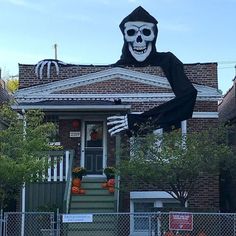 a house decorated for halloween with a skeleton on the front porch