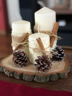 some candles are sitting on a wood slice with pine cones and cinnamon sticks tied around them