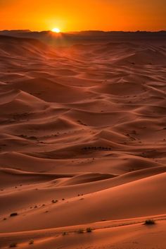 the sun is setting over some sand dunes