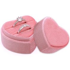 an open pink heart shaped box with two wedding rings in it's center and one diamond ring on top