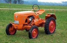 an orange tractor parked on top of a lush green field