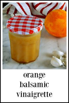 an orange balsamic vinaigrete in a jar next to garlic and an orange