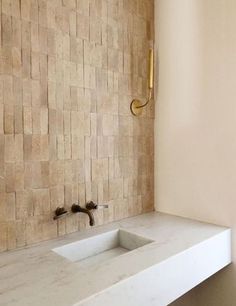 a white sink sitting next to a wall mounted faucet in a bathroom under a window