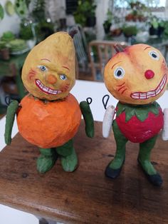 two clay figurines sitting on top of a wooden table