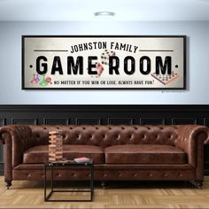 a brown leather couch sitting in front of a wooden wall with a game room sign above it