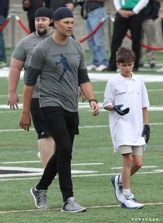 a man walking with a young boy on a football field in front of other people