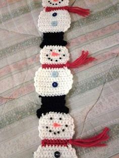 crocheted snowmen are lined up on the bed