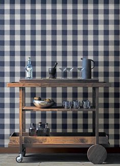 a wooden cart with cups and glasses on it in front of a checkered wall