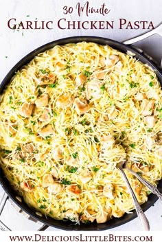 a skillet filled with pasta and chicken on top of a white tablecloth next to silverware