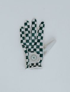 an oven mitt covered in white and green checkerboard pattern sitting on top of snow