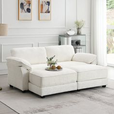 a living room with a white couch and two framed pictures on the wall above it