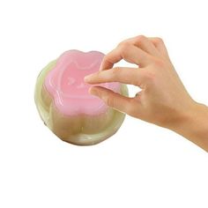 a hand holding a soap bar in front of a white background with pink and yellow swirls