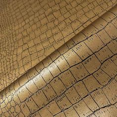 the texture of an alligator skin leather is shown in gold and brown tones, as well as black lines