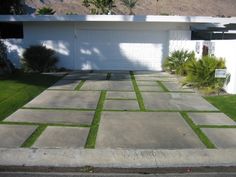 a driveway with grass in front of a house