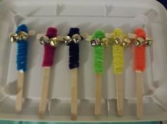 four toothbrushes with different colors and sizes in a box on a table next to some gold bells