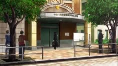 two people standing in front of an entrance to a building with trees on either side