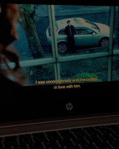 a laptop computer with a movie on the screen and a man standing in front of a car