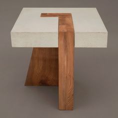 a white table with wooden legs and a square shaped design on the top, against a gray background