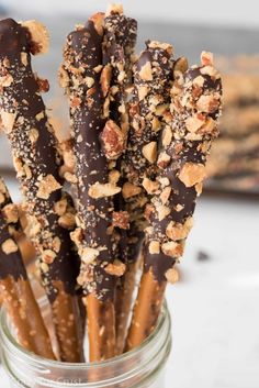 chocolate covered pretzels in a glass jar with walnuts on the top and crumbs on the bottom