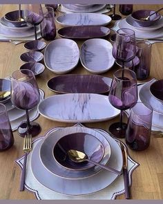 the table is set with purple dishes and silverware