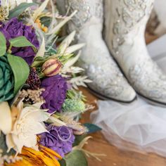 the bride's bouquet and cowboy boots are sitting on the table next to each other