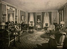 an old black and white photo of a living room with chairs, couches, lamps and pictures on the walls