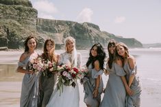 a group of women standing next to each other on top of a beach near the ocean