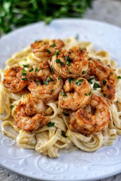 pasta with shrimp and parmesan cheese on a white plate next to fresh herbs