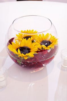 sunflowers are placed in a bowl on a white table top with other items