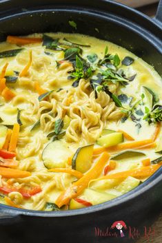 a pot filled with noodles and vegetables on top of a table