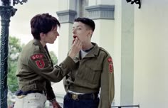 two people in uniforms standing next to each other and one is holding his mouth open