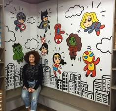 a woman sitting in front of a wall with cartoon characters on it