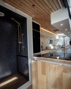 the inside of a boat that has a shower and sink in it, with wood paneling on the ceiling