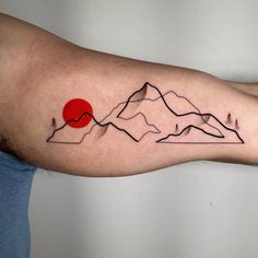 a man's arm with mountains and a red sun tattoo on the left forearm