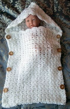 a crocheted baby blanket with buttons on it and a doll in the middle