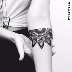 a woman's arm with a black and white tattoo design on the left forearm