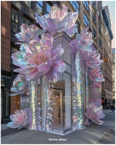 an art installation in front of a building with large pink flowers on the side of it