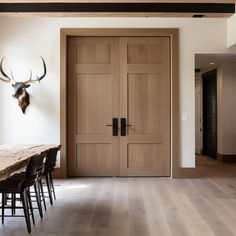 a dining room table with chairs and a deer head mounted on the wall