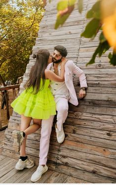 a man and woman are leaning against a wooden wall with their arms around each other