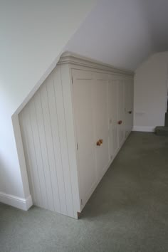 an empty room with white cupboards in the corner and carpeted flooring on the other side