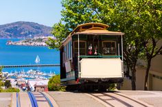 a cable car is going down the tracks near some trees and boats in the water