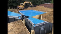 an image of a construction site with blue tarps on the ground and bulldozers in the background