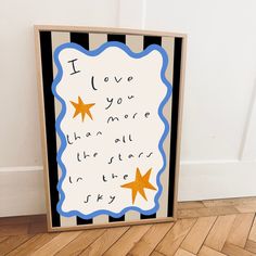 a wooden sign with writing on it sitting in front of a white wall and wood floor