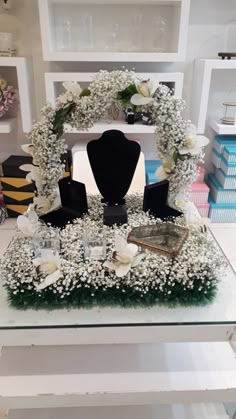 a table with flowers and jewelry on it in front of a shelf filled with books