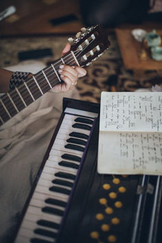 a person playing an electric guitar next to a sheet of music and a piano keyboard