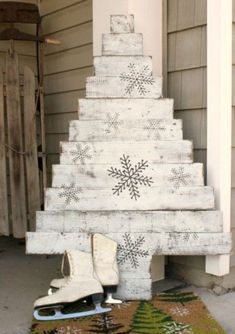 a christmas tree made out of wooden boards with snowflakes on it and two pairs of ice skates underneath