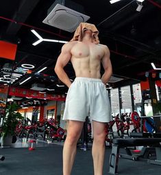 a man standing in the middle of a gym with his hands on his hips wearing shorts