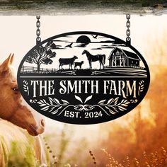 the smith farm sign is hanging from a chain in front of a horse and barn