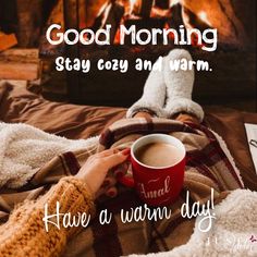 someone is holding a cup of coffee while sitting in front of a fireplace with the words good morning stay cozy and warm have a warm day